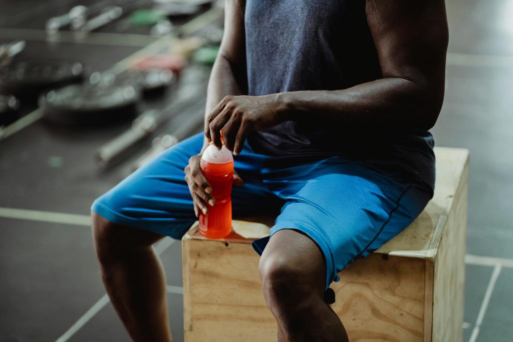Man sitting on a box holding a drink.