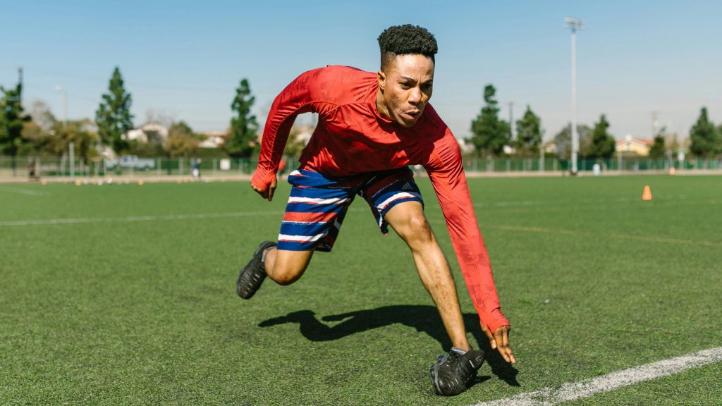 Guy doing drills on a football field.