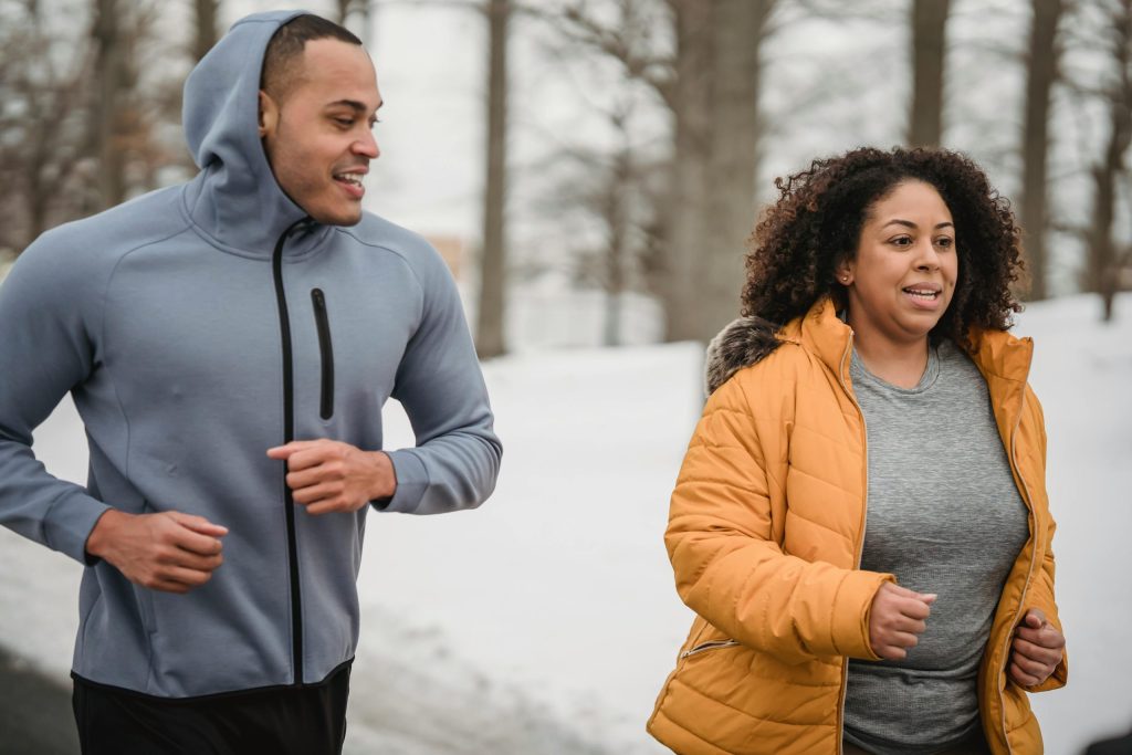 Trainer supporting woman during running workout in park.