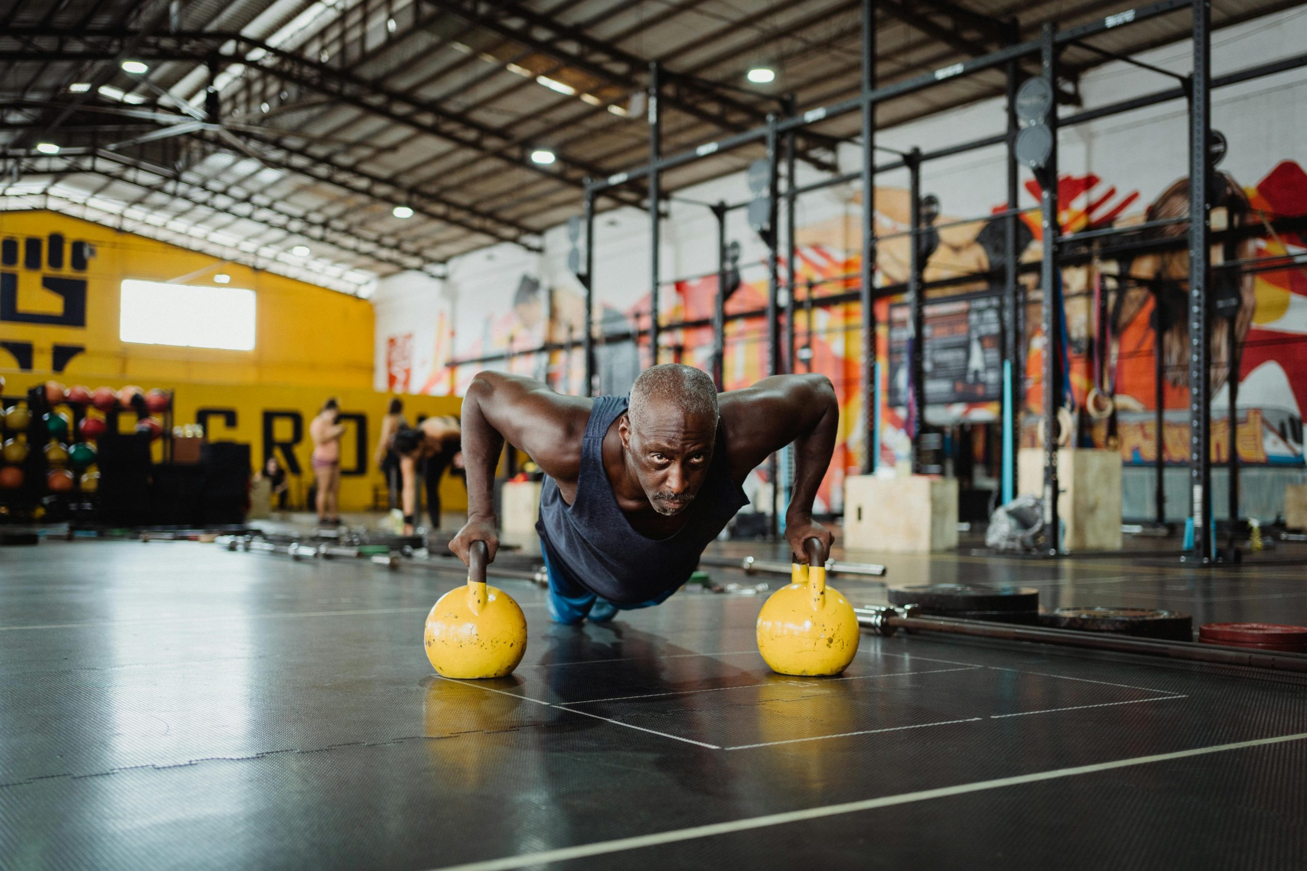 Black guy doing push-ups with kettle bells.