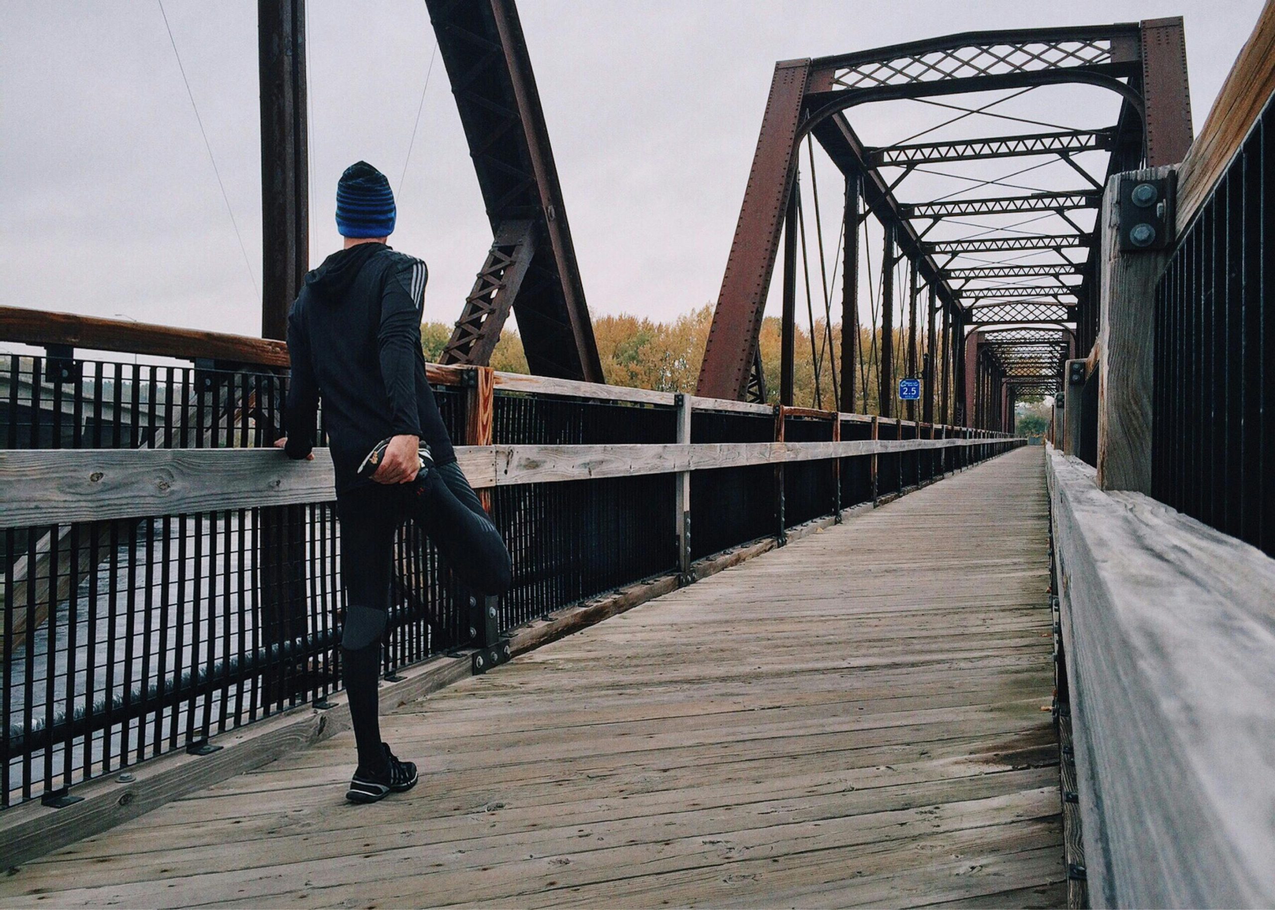 Guy stretching his legs on a bridge