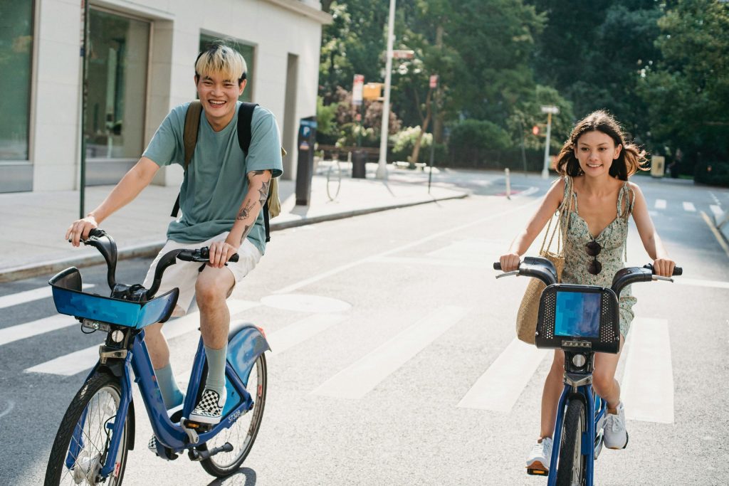 A guy and a girl biking together in the street.
