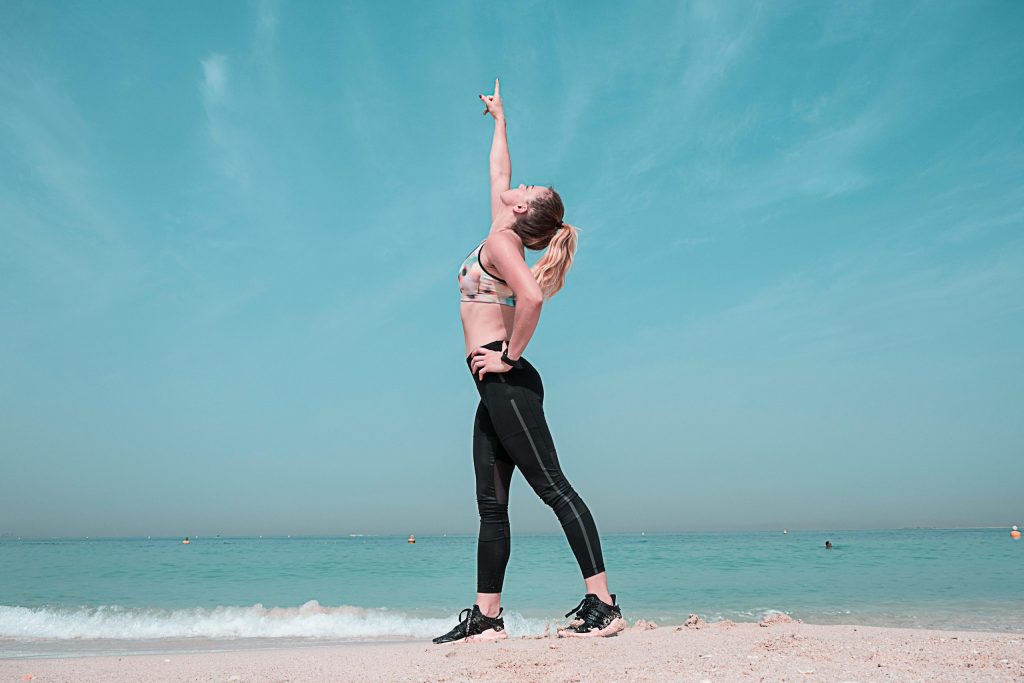 Woman on beach pointing towards the sky.