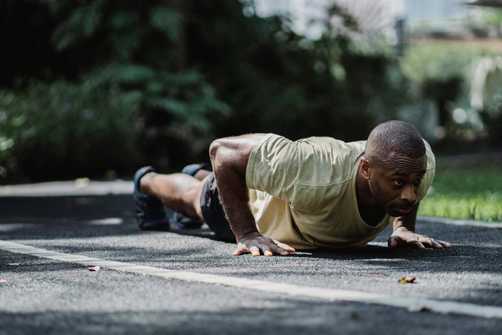 Man doing push-ups on the ground outside.