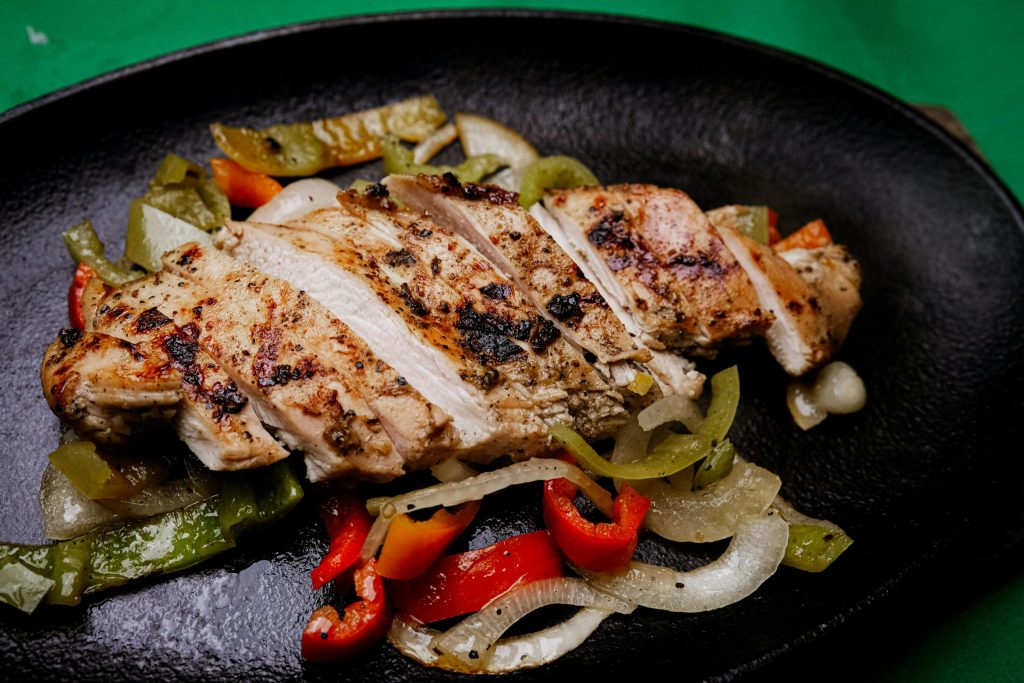Cooked chicken with peppers in a pan.