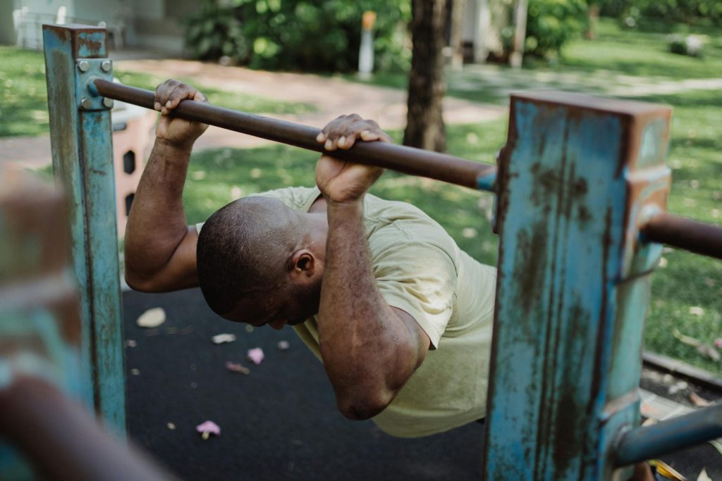 guy doing exercise in park using a bar